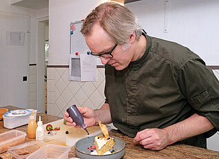 Auch optisch soll der Kuchen ein Genuss sein: Leon de Kok beim Ausdekorieren einer Torte; Foto: IW Medien